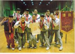 習志野高校女子体操部の生徒がジャージ姿でメダルをかけ賞状を持ち笑顔で集合写真を撮っている写真