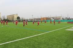 えんじ色のユニフォームを着たサッカー部が練習している様子の写真