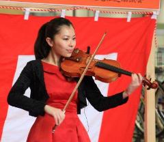 紅白幕の前で演奏しているヴァイオリニストの阿部志織さんをアップで撮影した写真