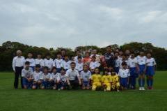 香澄小学校の女子児童と代表選手がグランドの芝の上で集合して記念撮影をしている写真