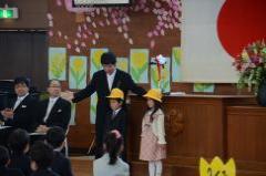 ステージの前で黄色い帽子をかぶって立つ男の子と女の子の写真