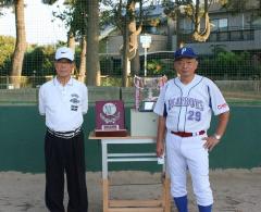 優勝カップや盾が置かれた机の前に立っている男性2名の写真