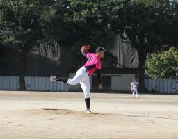 ピンク色のユニフォームを着た投手が力投する様子の写真
