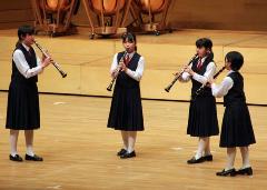 半円状に並び中央を向き、クラリネットを吹いている制服を着た女子生徒4人の写真