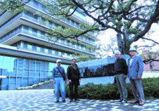 習志野市役所前で4人の市民カレッジOB有志会の皆さんが並んで写っている記念写真
