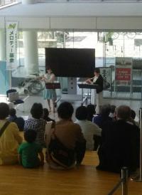 市役所グランドフロアでのロビーコンサートに集まる人たちと五十嵐由美さんと星野美波さんの写真
