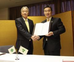 宮本市長が協定書を左手に持ち、右手で石井市長と握手を交わしている写真