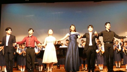 舞台上で、日本側出演者3名と韓国側出演者3名が手をつないで歌っている写真