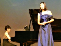 紫色のドレスを着て歌を歌っている井出瑠葦さんの写真