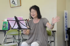 楽譜の前で椅子に座り、笑顔で指導する廣瀬先生の写真