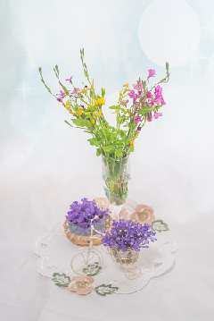花瓶に生けられたピンクと黄色い花、小さな容器に入った紫色の花の写真