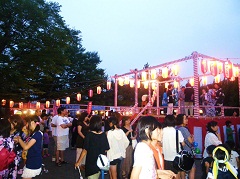 舞台に提灯が灯され盆踊りや夏祭りを楽しむ多くの参加者の写真