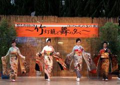 舞台の上で着物を着た4名の女性が横一列に並んで歩いている写真