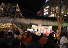 明かりのついたイルミネーションの周りに沢山の人が集まっているクリスマスコンサートの写真