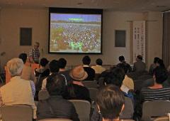 スクリーンを使って資料を映しながら、谷津干潟に関する講演を行う木村尚講師と講演を聞く参加者の方々の写真