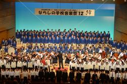 大きな舞台の上に大勢の制服姿の学生さんが集まった、ならしの学校音楽祭の集合写真