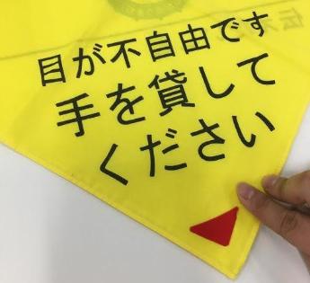 黄色の布地に「目が不自由です手を貸してください」と書かれ、表裏を間違わないようにフェルトの生地が使われているスカーフのフェルト部分の写真