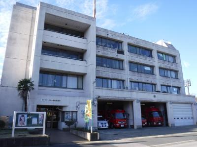 白い外壁で4階建て、1階の車庫に救急車と消防車が停まっている秋津出張所の建物の写真