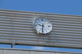 屋上のフェンスに設置された時計をアップで写した写真