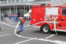 消防車の横からホースを持ち走り出している消防員の写真
