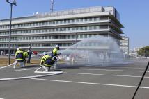 駐車場で2組に分かれ放水をしている写真