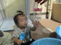 子どもが水に手を伸ばして遊んでいる様子