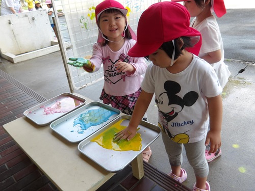 バット上の絵の具に慎重に手をつける3歳児