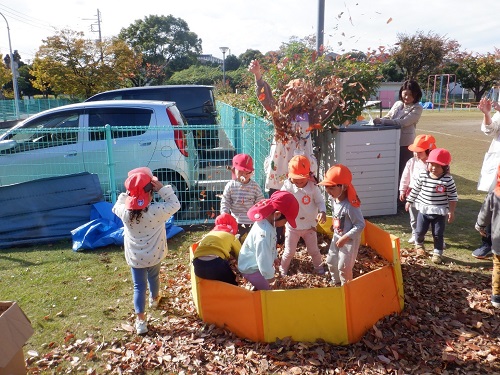 3歳児が落ち葉で遊んでいる様子