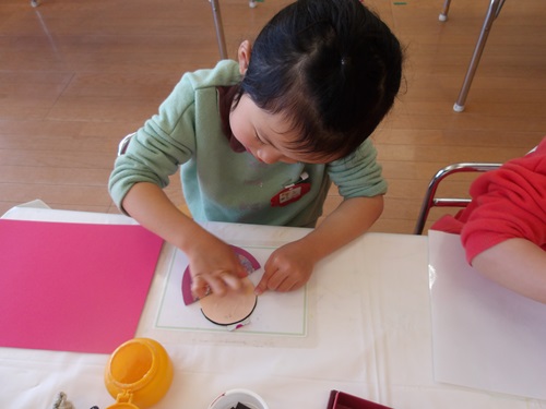 3歳時が雛人形を作ろうとのりを塗っている様子