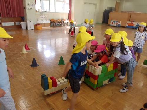 5歳児が作ったBブロックの乗り物に4歳児を乗せてあげる様子