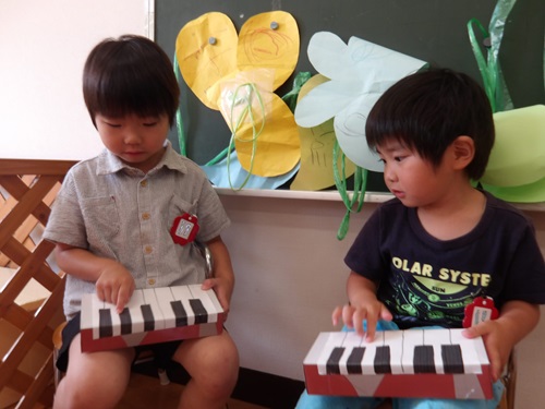 3歳児が友達と空き箱のピアノを弾いている