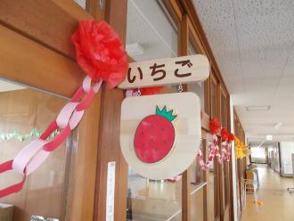 部屋の入り口に木製の板にイチゴの絵が描かれているいちご組保育室の写真