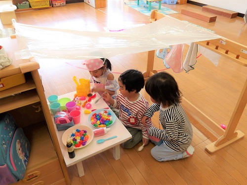 3歳児が3人でままごと遊びをしている様子