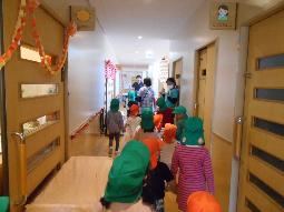 年長児が年中組の子どもたちと手をつなぎ、園内めぐりをしている様子