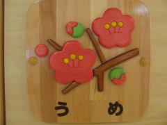 梅の花の絵が描かれたうめ組の木製プレートの写真