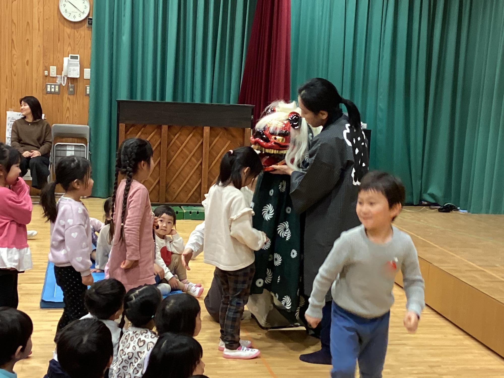 獅子舞が頭をかむ