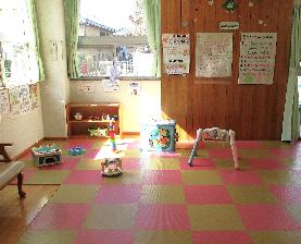 杉の子こども園の室内のジョイントマットの上にベビージムが設置されてあるあかちゃんコーナーの写真