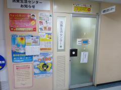 左壁にチラシやポスターが掲示されている消費生活センター入口の写真