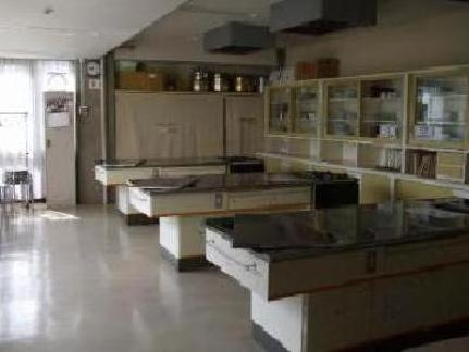 室内右側に食器棚が置かれ、食器棚向かい側に調理台3台がある調理室の写真