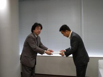 向かい合ってお辞儀をしながら答申書を手渡している朝倉会長と審議会の方の写真