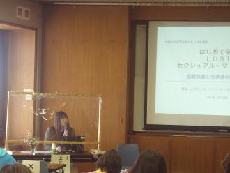 資料が映しだされた大きなスクリーンの横でマイクを使いながら話をする講師上井ハルカさんの講演写真