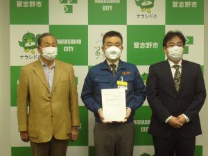 中央で宮本市長が答申書を持ちその両サイドに朝倉会長と赤城部会長が立っている写真