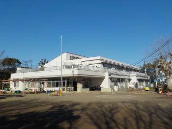 手前に広い園庭が広がり、奥に谷津南保育所の白い園舎が建っている写真