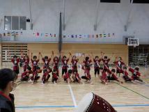 体育館で行われた太鼓のリズムに合わせて赤い服を着た子供たちが踊りを披露している様子の写真