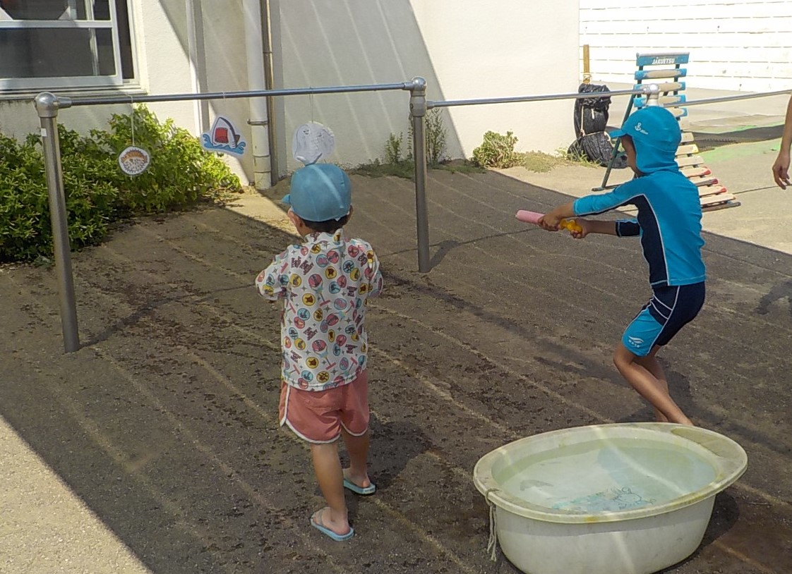 水鉄砲で鉄棒に吊り下げてある的をねらっています。
