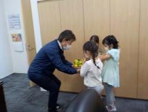 校長先生に3人の子供が黄色の花束を渡している様子の写真
