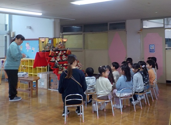 7段飾りの前で雛人形について話を聞いているところです。