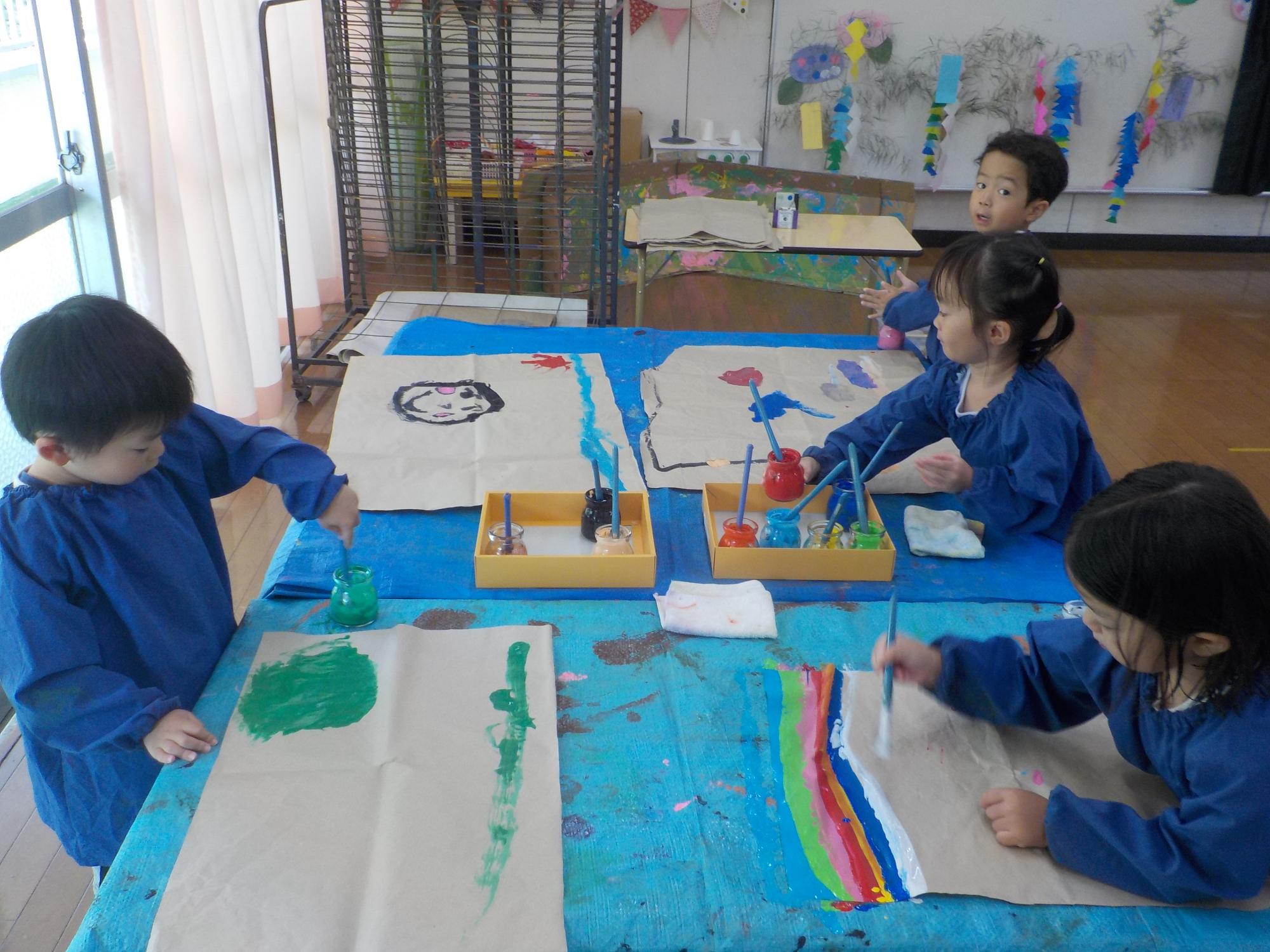 年少組が筆で絵の具を使って思い思いの絵を描いています。