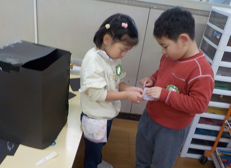 ヒヤシンスの部屋の箱を持ち上げられるようプリンカップで持ち手をつけようとしています。