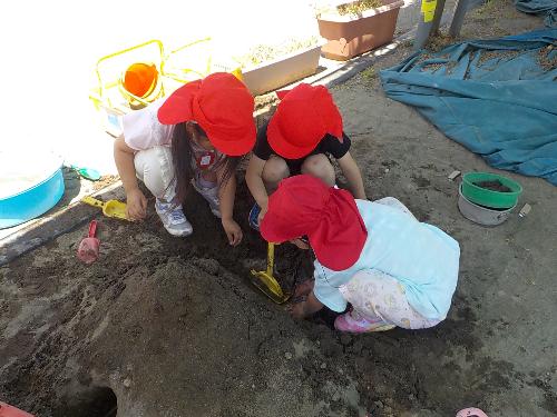 4才児が砂場で山を作って遊んでいます